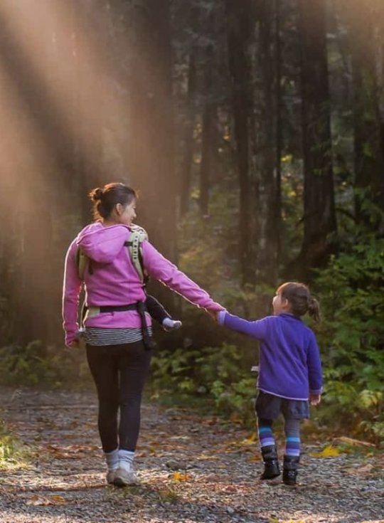 mati in hči z roko v roki na sprehodu po gozdnih poteh