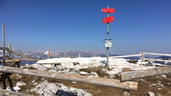 krožno zagrajen rdeč smerokaz na vrhu Tolstega vrha s panoramo gorovja
